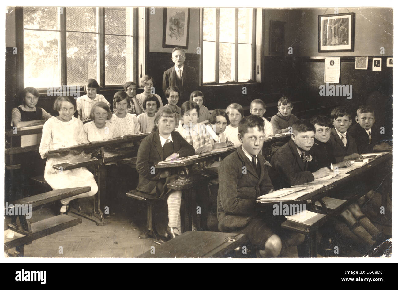 Postkarte von einem Lehrer mit Juniorinnen & Jungs sitzen an ihrem Schreibtisch, mit offenen Bücher im Klassenzimmer, 1940er Jahre, U.K Stockfoto