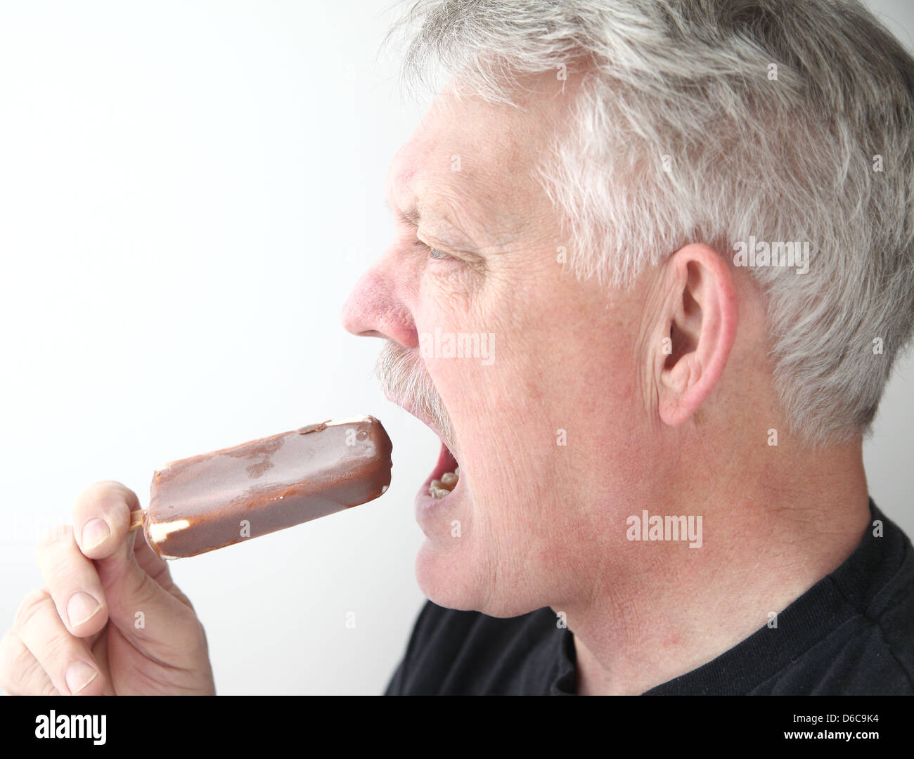 ein älterer Mann isst eine Schoko-Eis-bar Stockfoto
