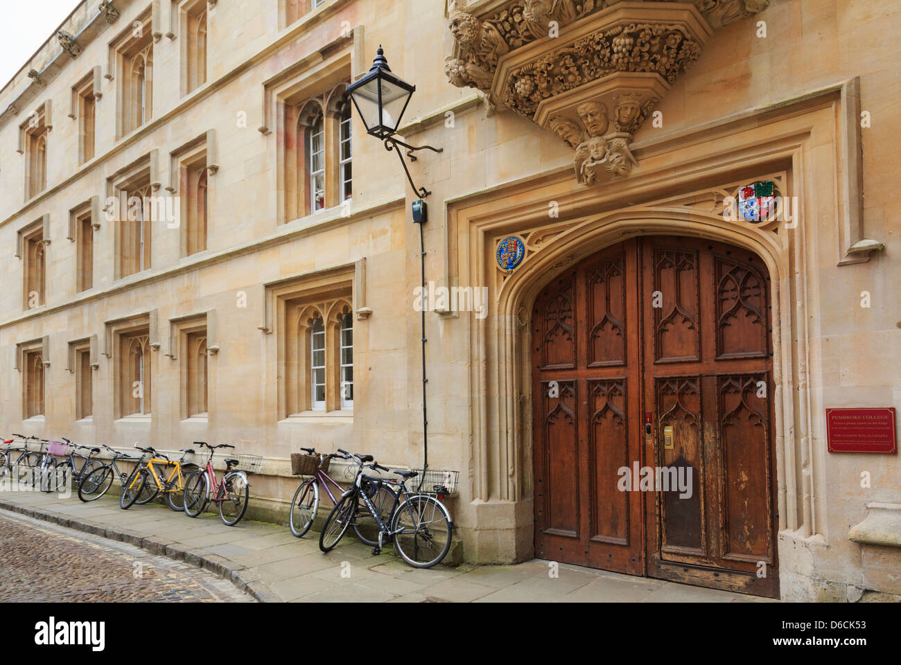 Oxford, Oxfordshire, England, UK. Pembroke College alte hölzerne Tür mit Fahrrädern an der Wand außerhalb Stockfoto