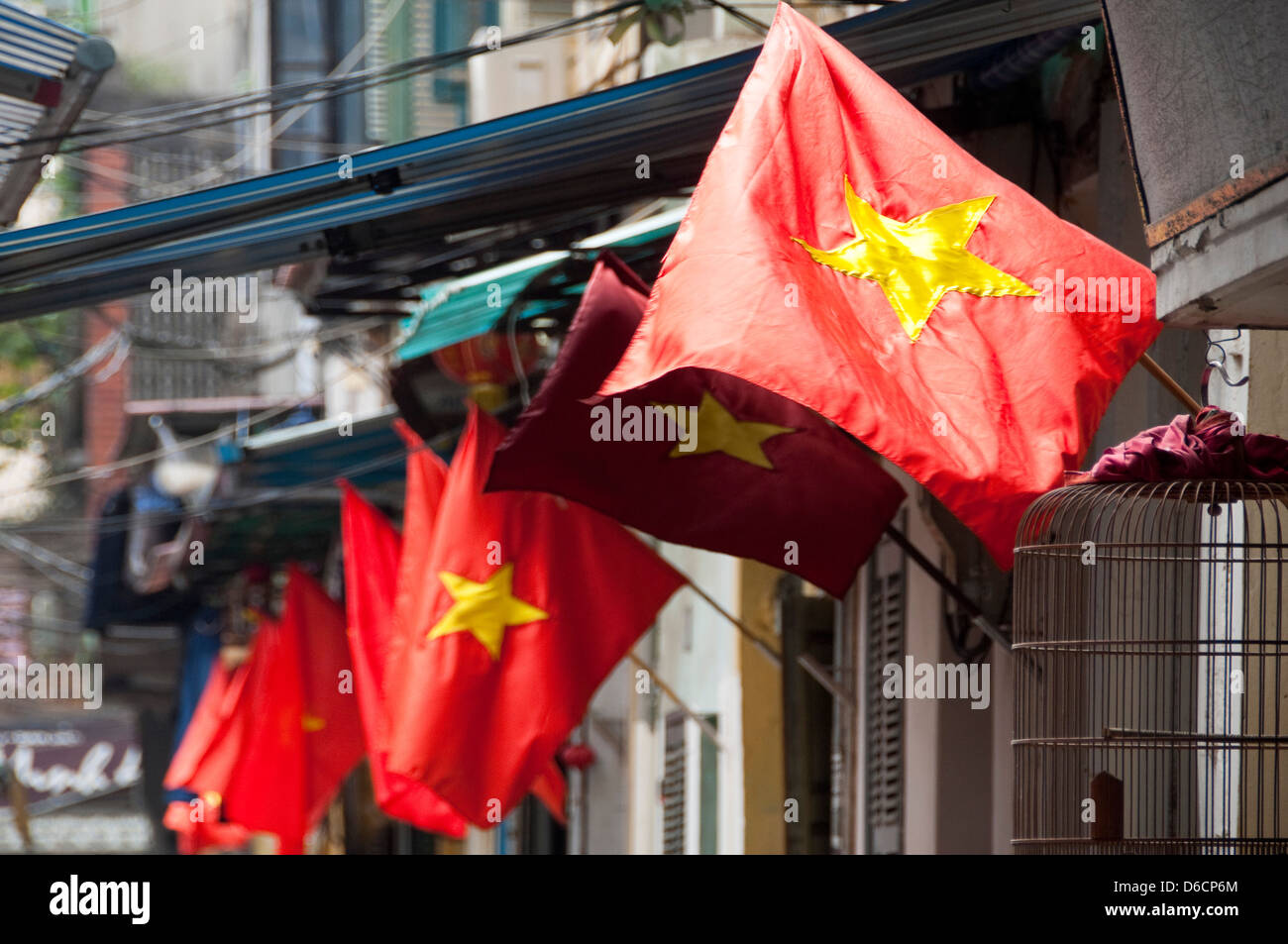 Horizontale Ansicht von vielen vietnamesischen Flaggen wehen im Wind außerhalb der Häuser. Stockfoto