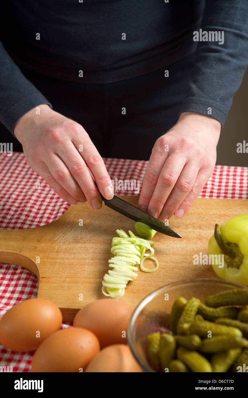 Weibliche Hände Lauch auf einem Brett Holz hacken mit schwarzer Keramik Messer schneiden. Stockfoto