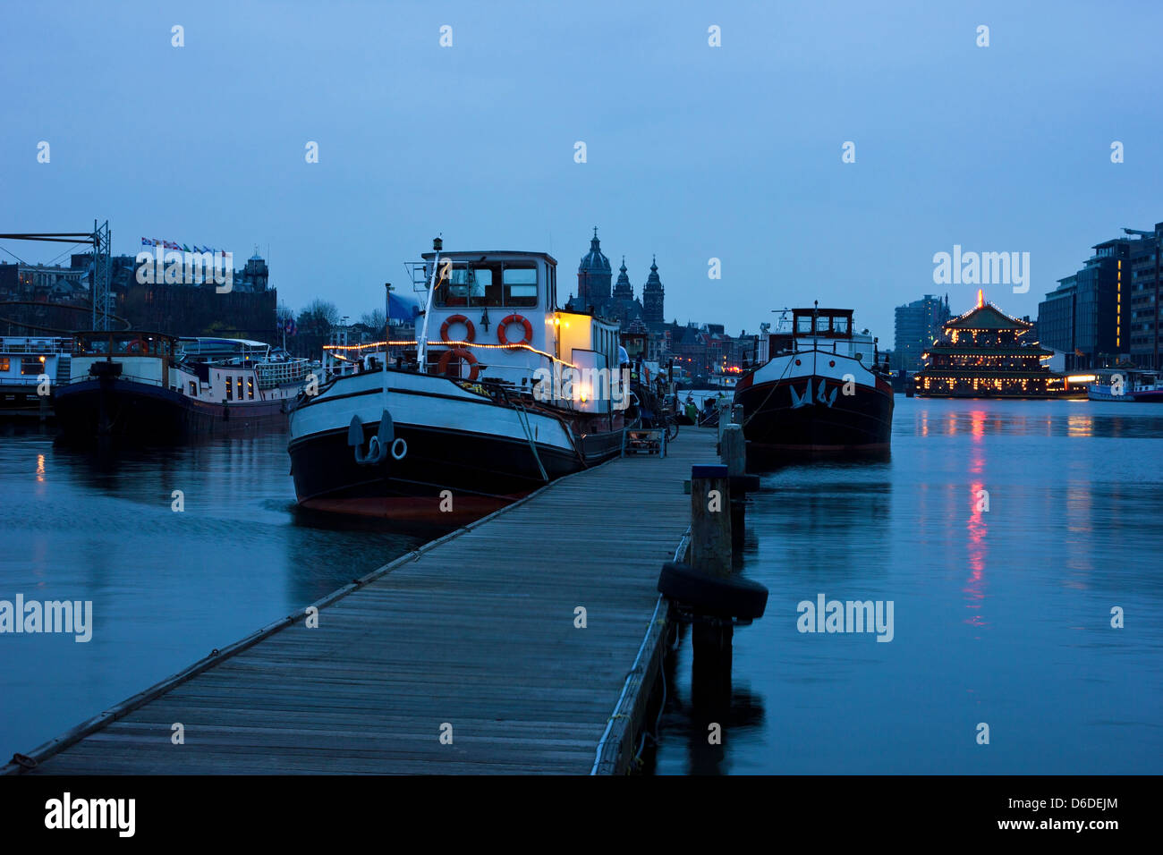 Hafen von Amsterdam Oosterdok vor Sonnenaufgang mit der St.-Nikolaus-Kirche im Hintergrund. Stockfoto