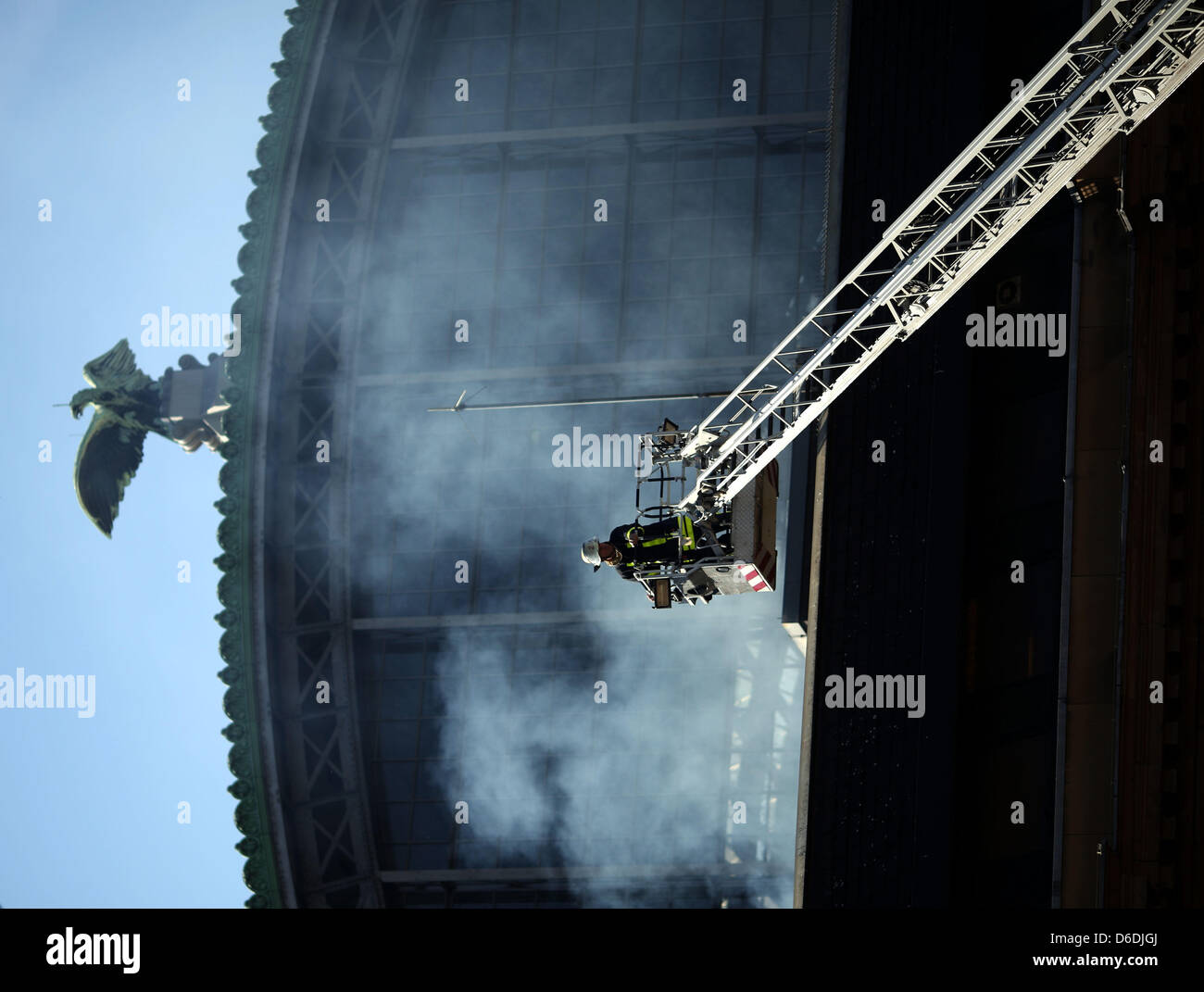 Ein Feuerwehrmann steht auf einer Leiter neben einer Wolke aus Rauch steigt vom Dach eines Flügels der Hauptbahnhof in Frankfurt Main, Deutschland, 7. September 2012. Ein Stromausfall am frühen Nachmittag beeinflusst die Lichter und zeigt am Bahnhof. Foto: FRANK RUMPENHORST Stockfoto