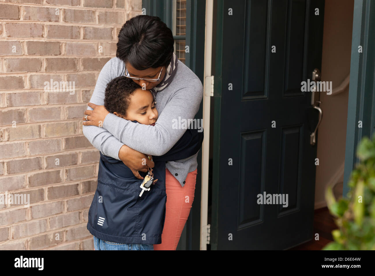 Mutter umarmt Sohn an Haustür Stockfoto