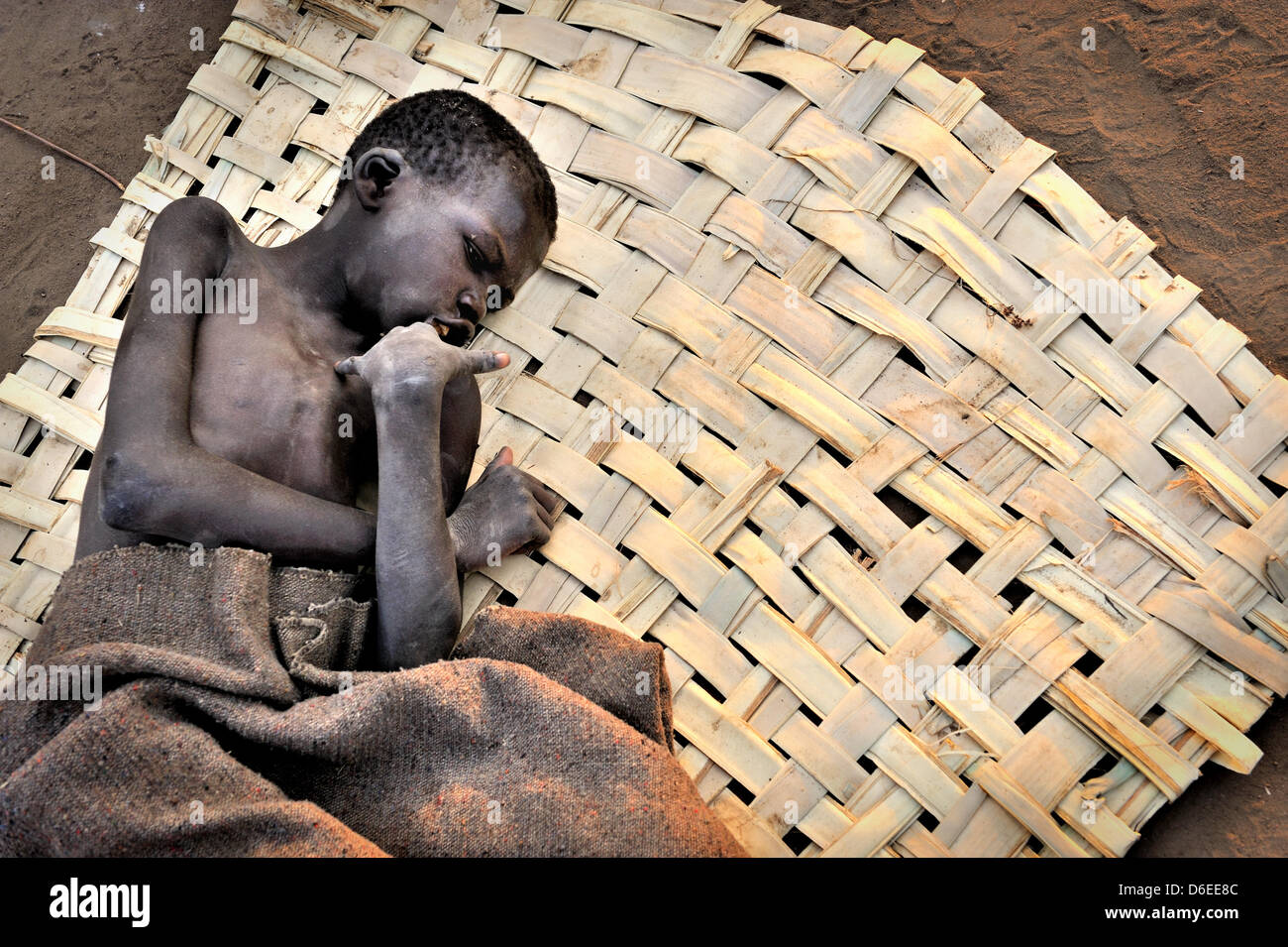 Patrick Anywar (14) liegt auf einer Matte vor einer Hütte im Bezirk Kitgum, Norduganda, 17. Januar 2012 abgemagert. Er leidet unter Nodding Krankheit, die eine neue, unbekannte Krankheit, die im Sudan in den 1980er Jahren erschien. Kranken, Kinder zwischen fünf und 15 Jahre alt, sind körperlich und geistig verkümmert. Den meisten Fällen im Moment sind im Norden Ugandas und im Südsudan. Stockfoto