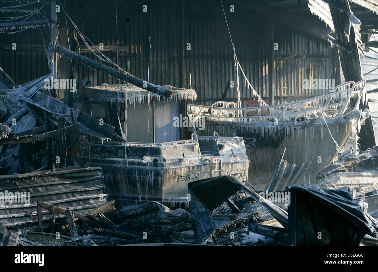 Die Reste der verbrannten zwei Yachten Sit bedeckt mit gefrorenem Wasser von Polizeihunden sitzen in einem ausgebrannten Bootshaus in Hamburg, Deutschland, 31. Januar 2012. Ein Feuer brach in einem 30 x 50 Meter große Bootshaus und rund 50 Boote, darunter ein paar klassische Boote wurden durch das Feuer zerstört. Foto: DANIEL BOCKWOLDT Stockfoto