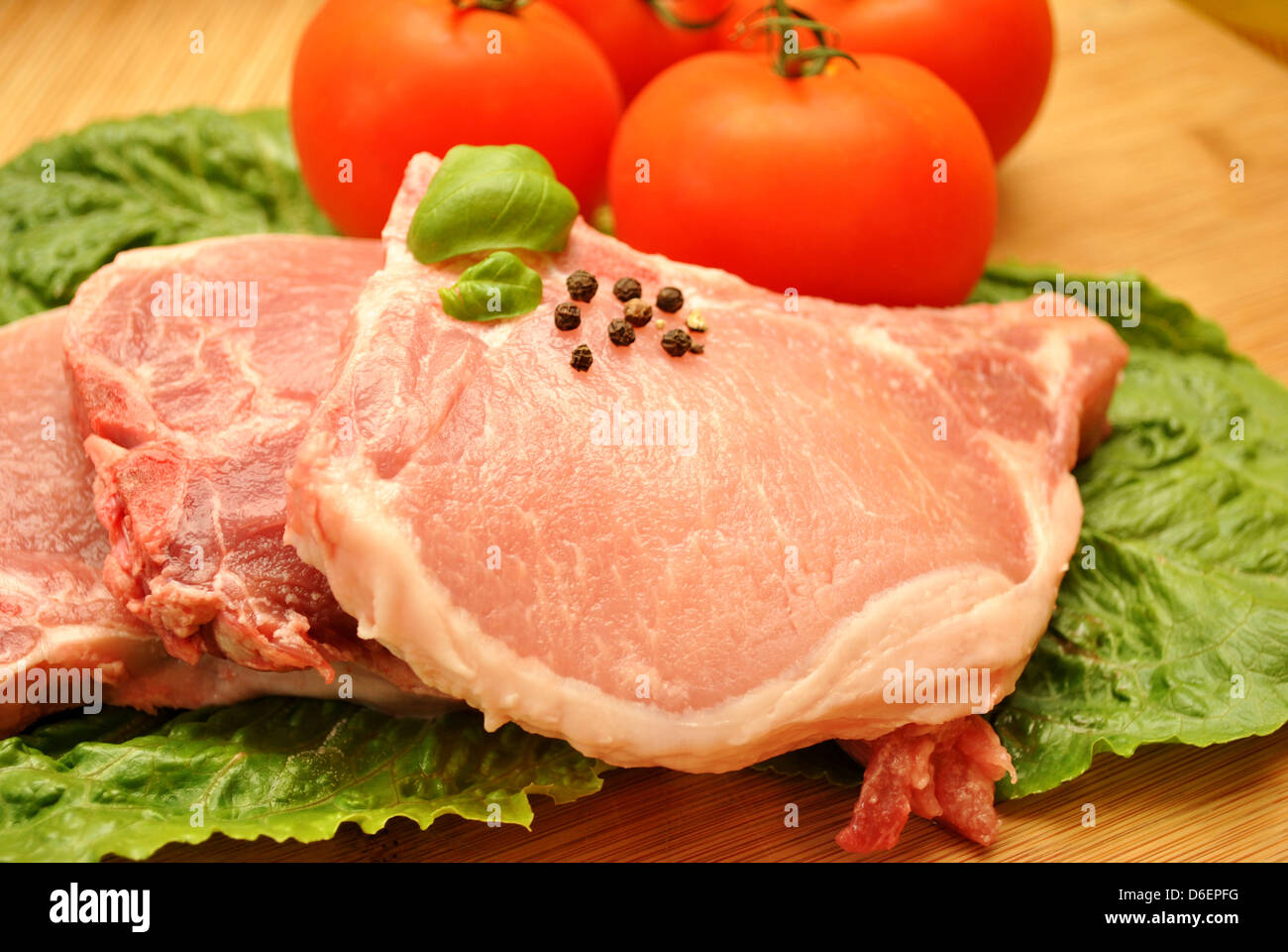 Ein rohes Schweinekotelett mit frischen Zutaten Stockfoto