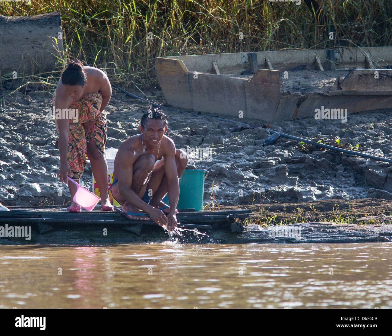 Ein junger Mann und eine Frau waschen im Fluss Kinabatangan in Sabah Borneo in den frühen Morgenstunden Stockfoto
