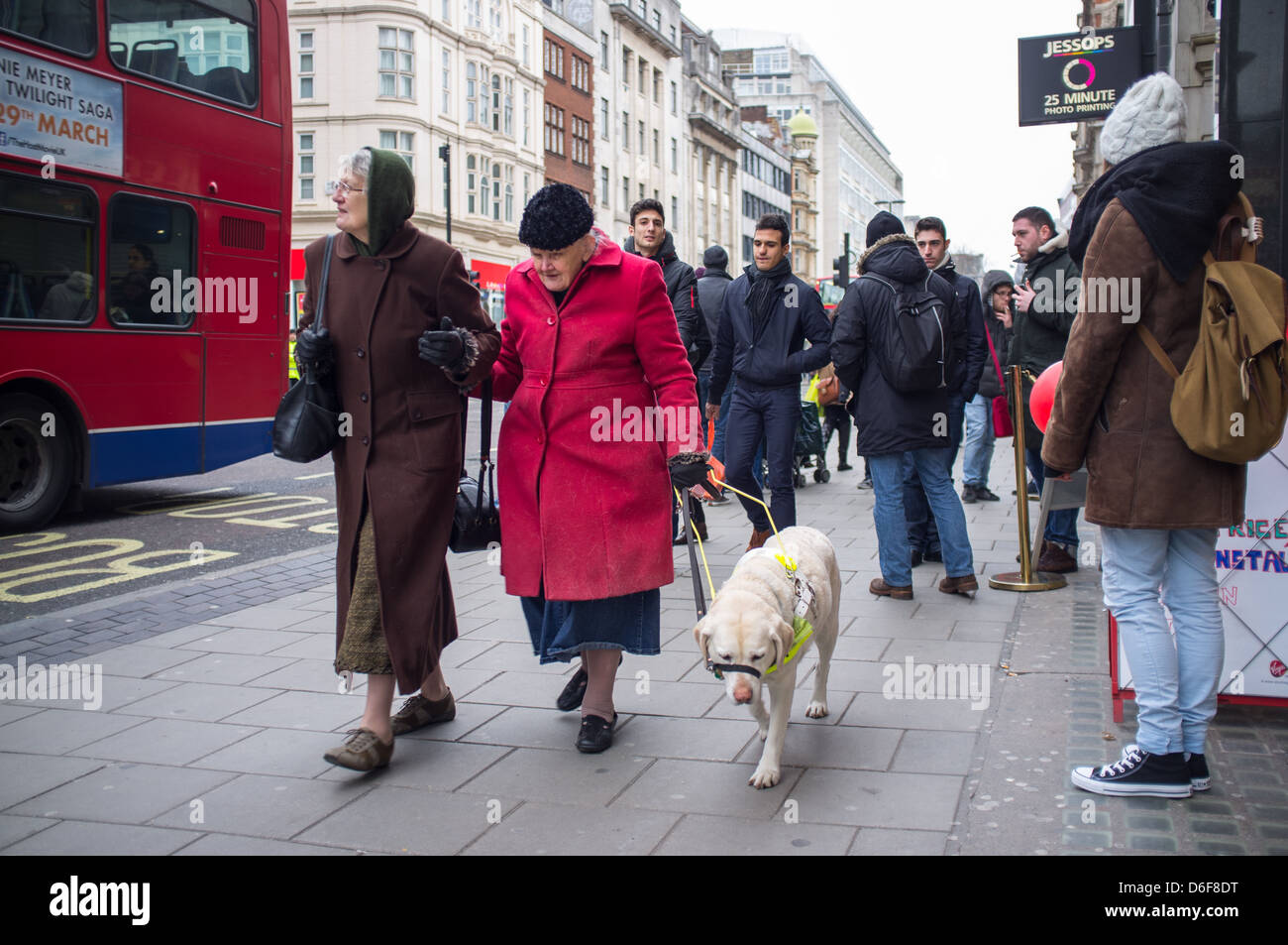 Zwei ältere Frauen, eine blinde oder Sehbehinderte, die ihren Weg durch die Menschenmassen auf der Oxford Street, London, UK Stockfoto