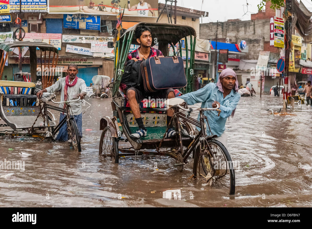 Monsun-Regen und grelle Flut noch Menschen gehen noch über ihr Geschäft in Varanasi, Uttar Pradesh, Indien. Stockfoto