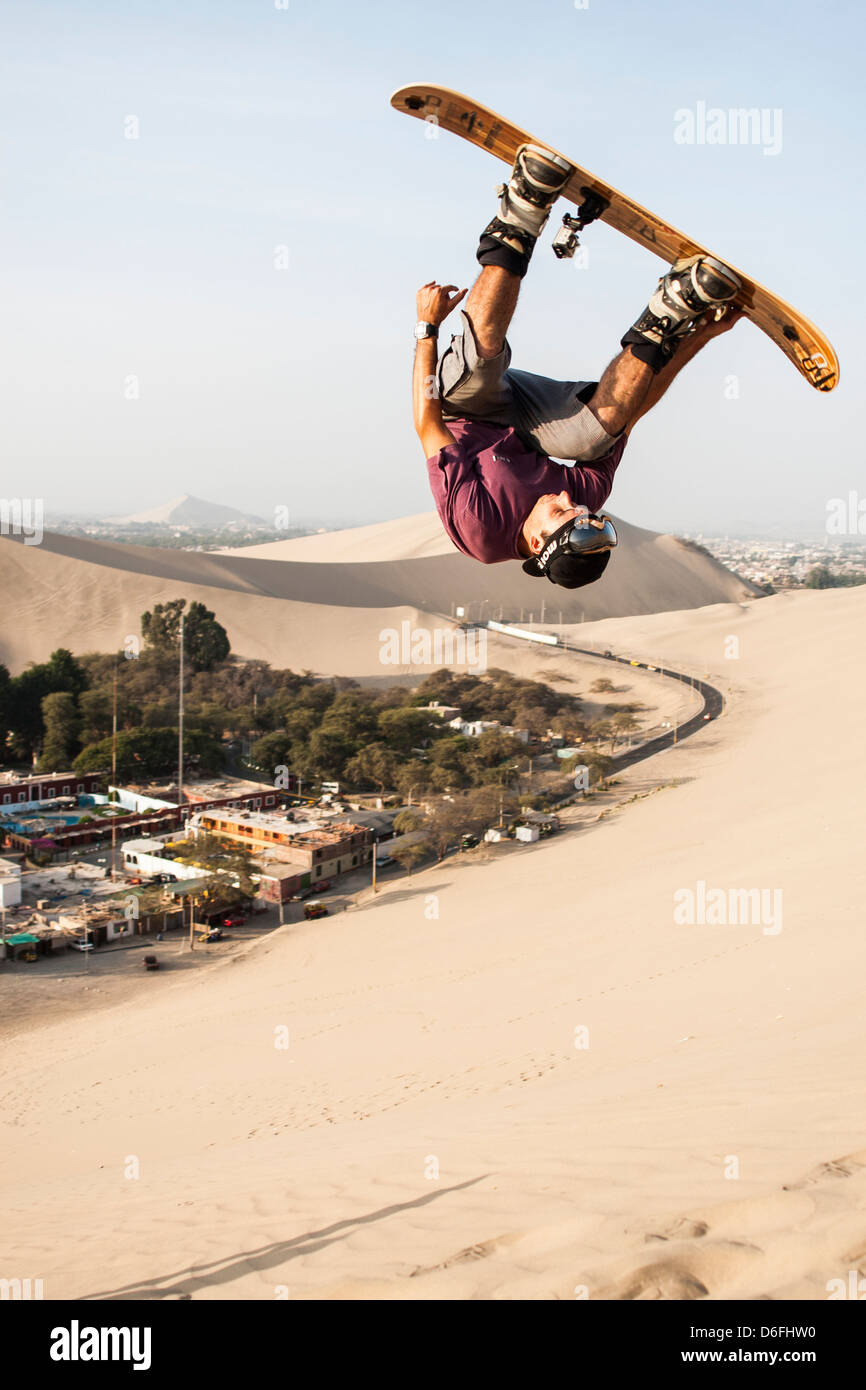 Junger Mann Sandboarding in Huacachina Oase. Stockfoto