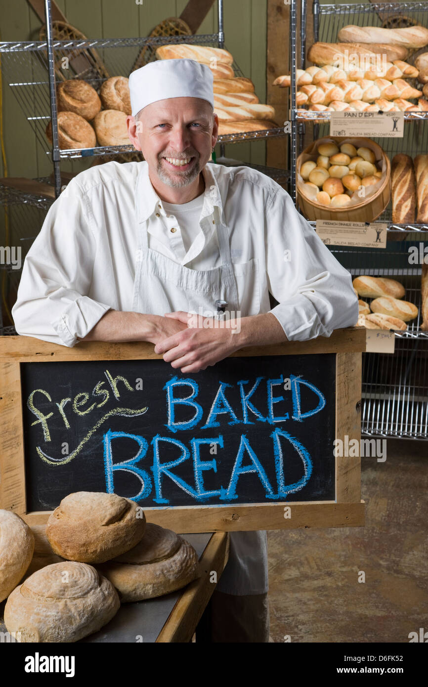 Porträt von professionellen Koch in seiner Bäckerei, umgeben von frisch gebackenem Brot Stockfoto