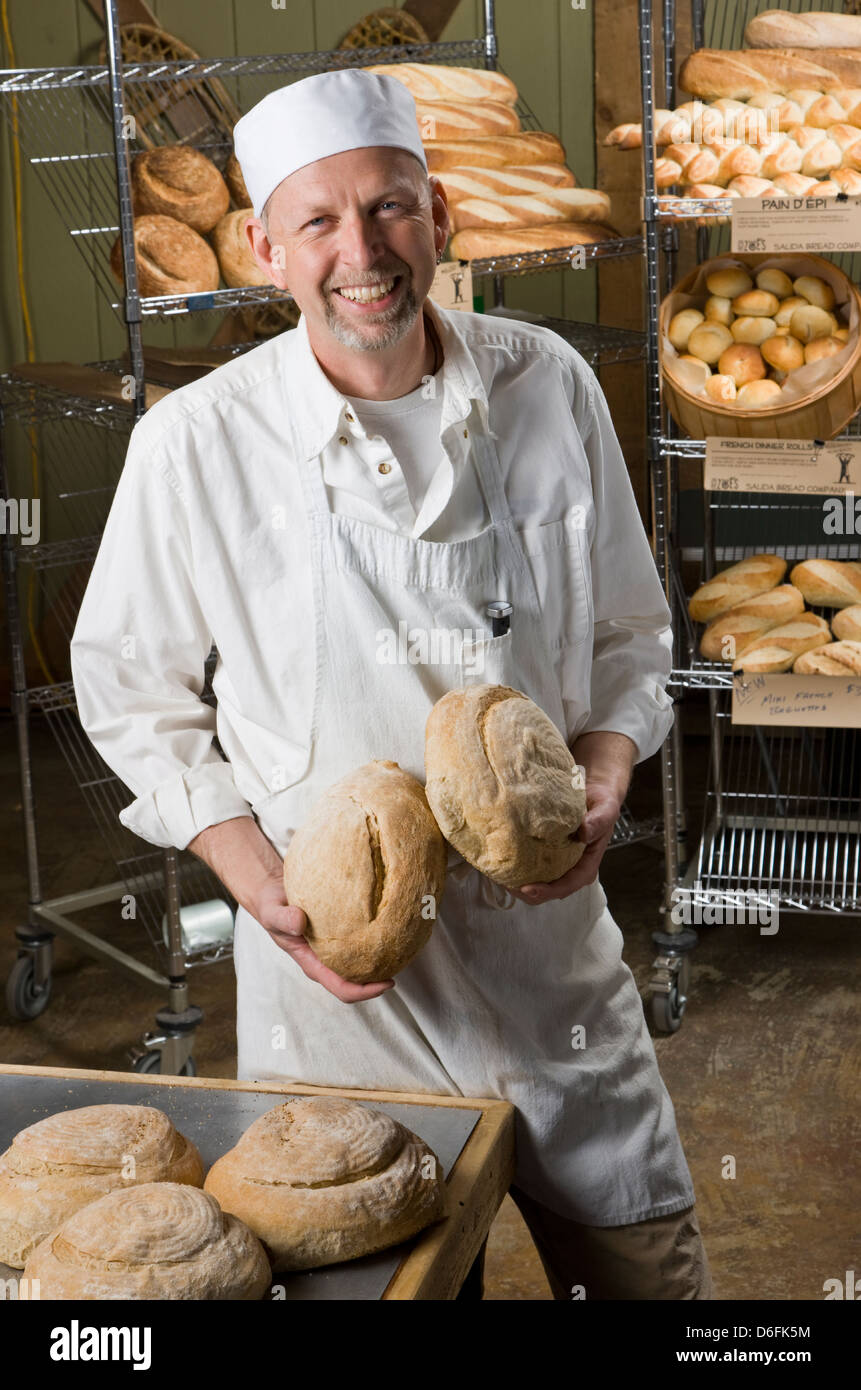 Porträt von professionellen Koch in seiner Bäckerei, umgeben von frisch gebackenem Brot Stockfoto