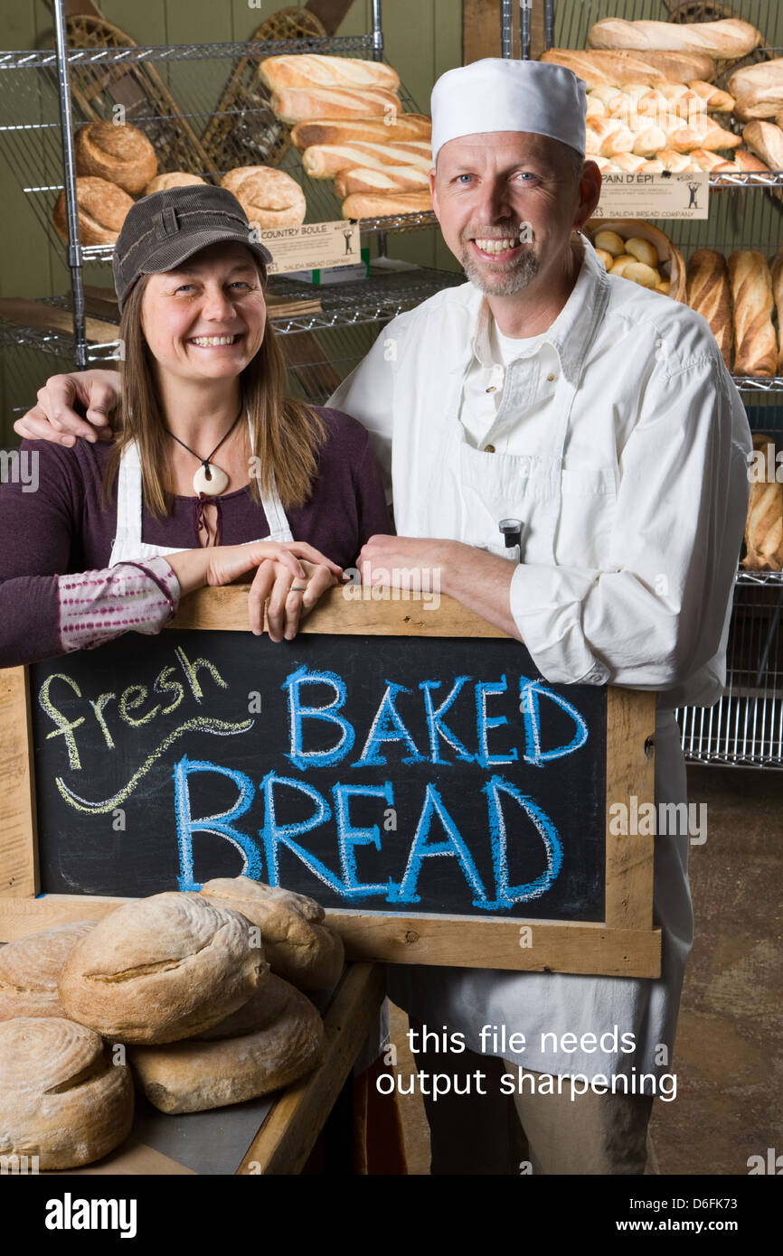 Porträt von Mann und Frau-Team in ihren kommerziellen Bäckerei, umgeben von frisch gebackenem Brot Stockfoto