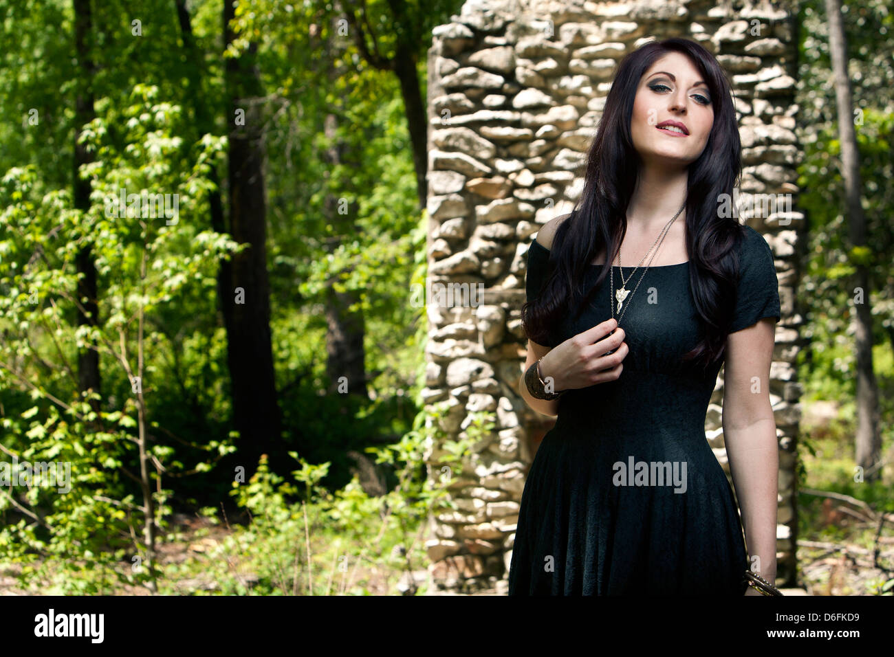 Frau im schwarzen Kleid vor steinernen Kamin Stockfoto