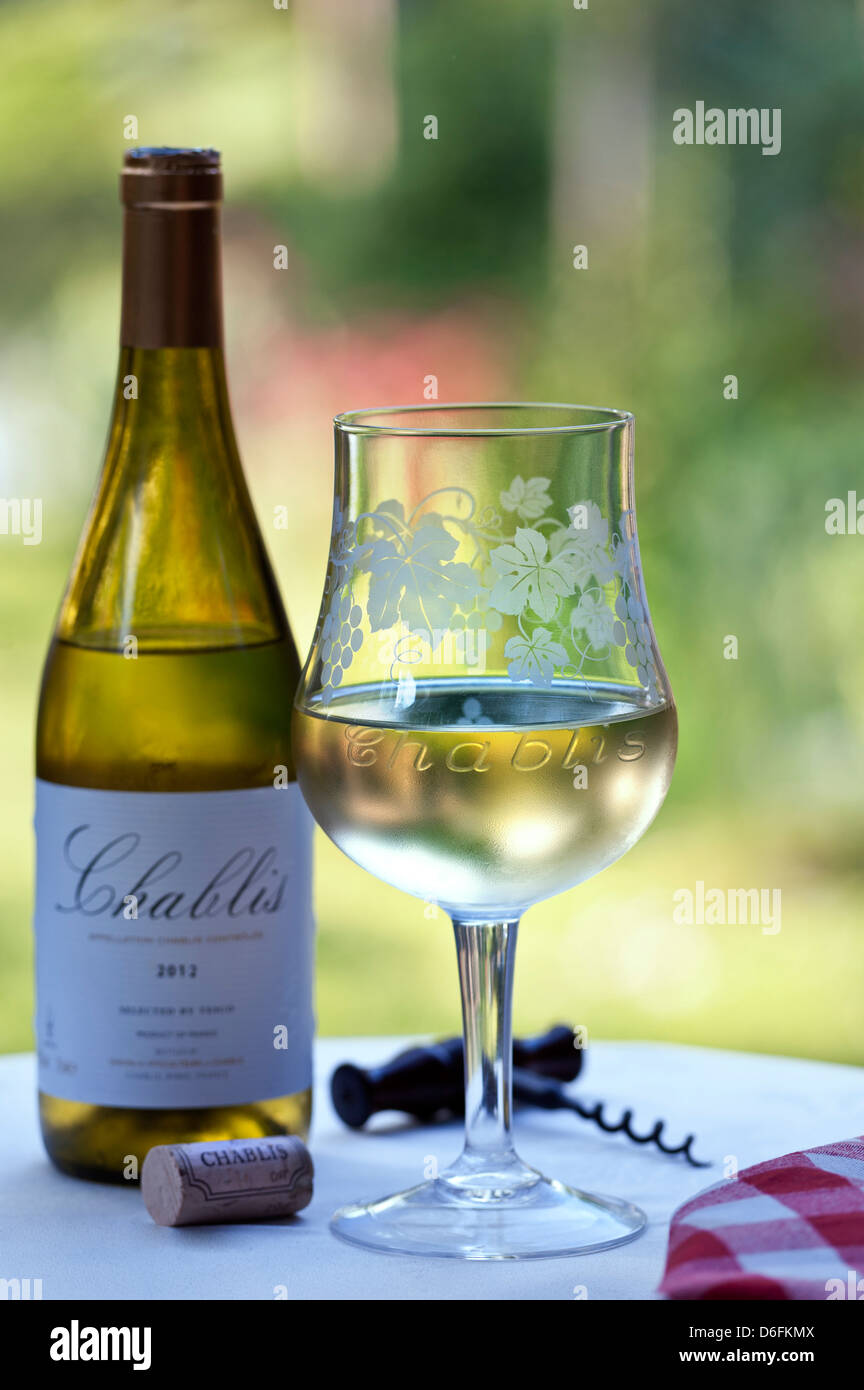 "Chablis" graviert Weingut tasting Glas Flasche Korken und Korkenzieher auf alfresco Terrasse Tisch in späten Nachmittagssonne Stockfoto