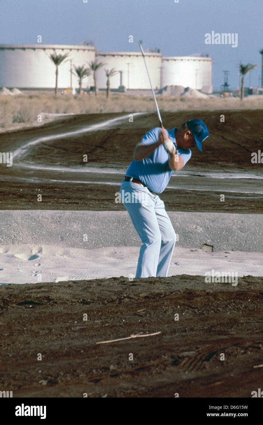 Amerikanische Mitarbeiter bei Saudi Aramco Golf auf dem Öl durchtränkten Sand auf der Firma Golf Course in Ras Tanura, Öltanks auf Rückseite. Stockfoto