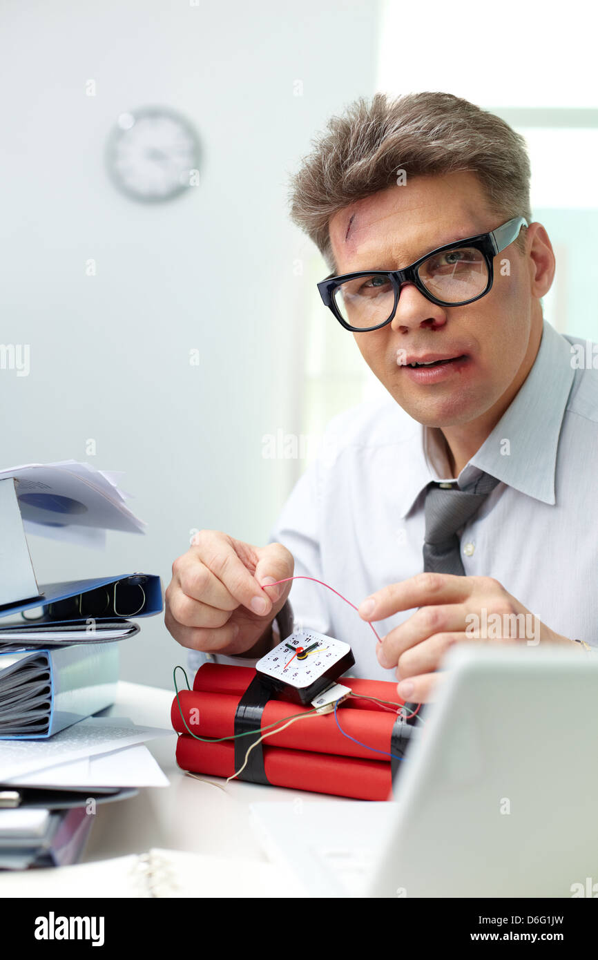 Ernster Mann Vorbereitung Dynamite mit großen Haufen von Papieren in der Nähe von Stockfoto