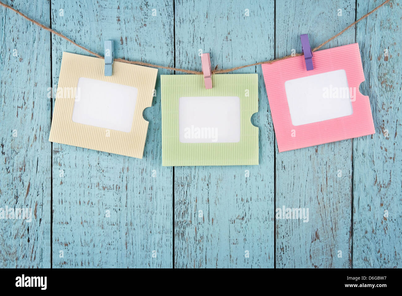 Drei leere bunte Bilder oder Notizen Fotopapier mit Wäscheklammern aus Holz blau Vintage shabby-chic Hintergrund hängen Stockfoto