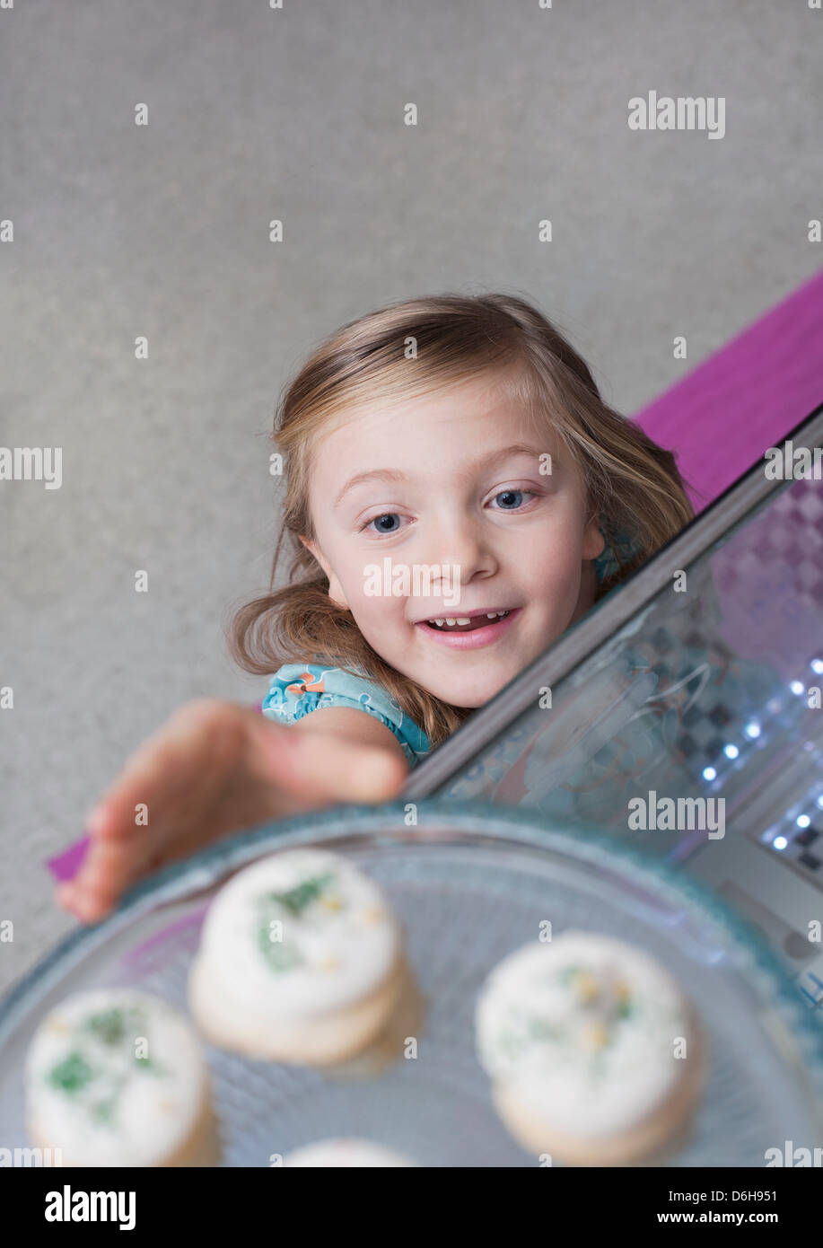 Mädchen erreichen für Cupcakes in Bäckerei Stockfoto
