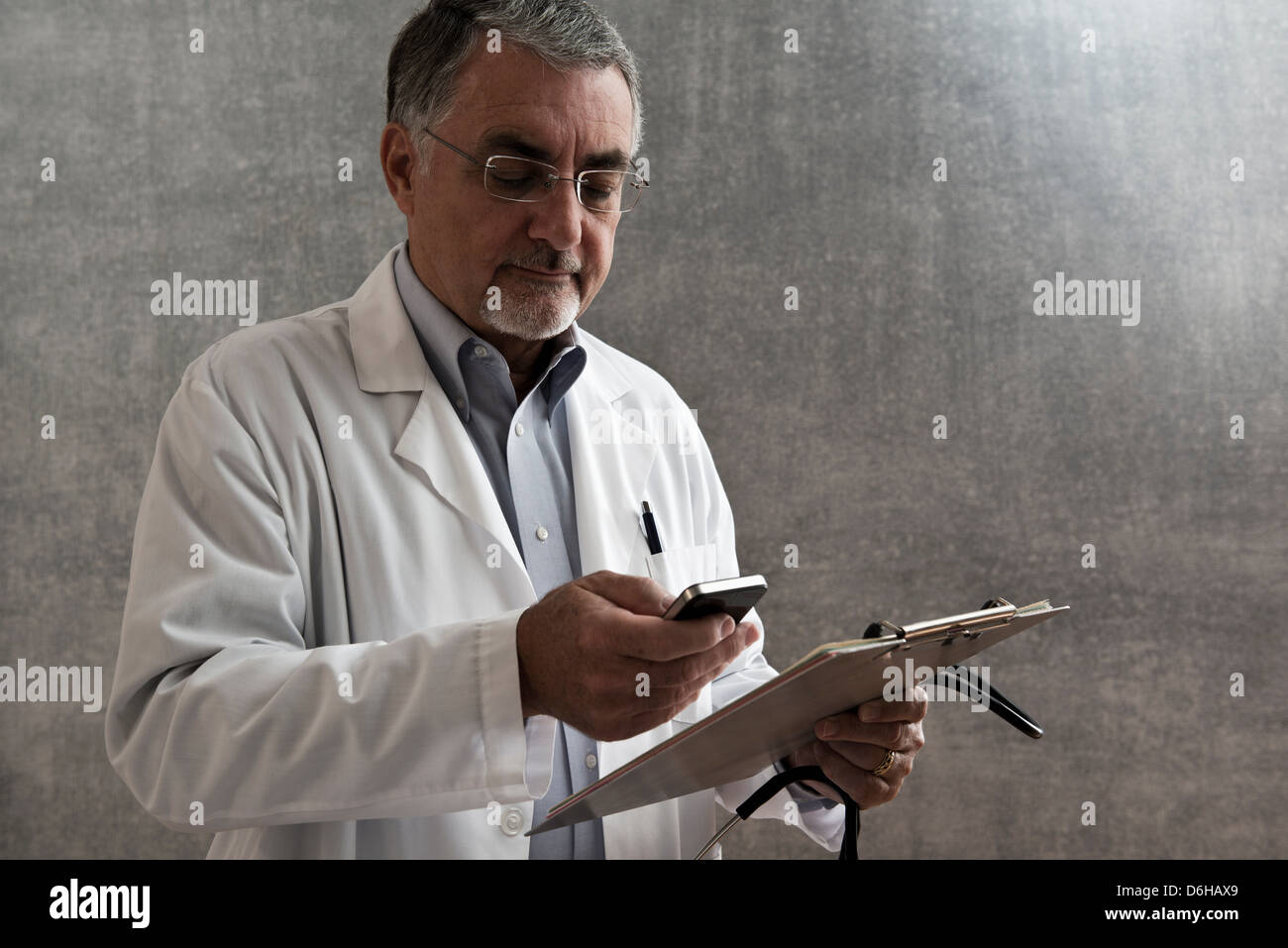 Männlichen Arzt mit Handy und Zwischenablage Stockfoto
