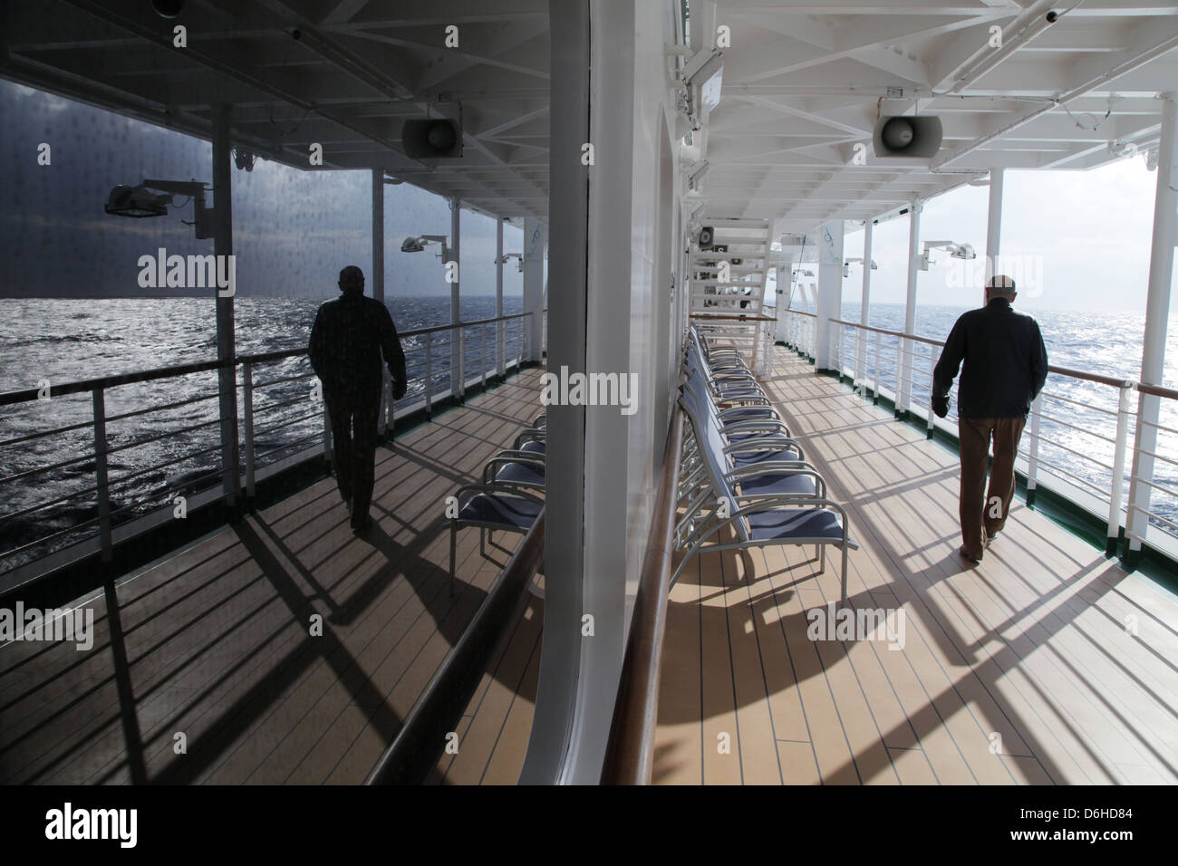 Ein älterer Mann geht auf dem Promenadendeck in der Sonne auf das Kreuzfahrtschiff P & O m.v. Azura Schiff auf einen Urlaub am Mittelmeer Stockfoto