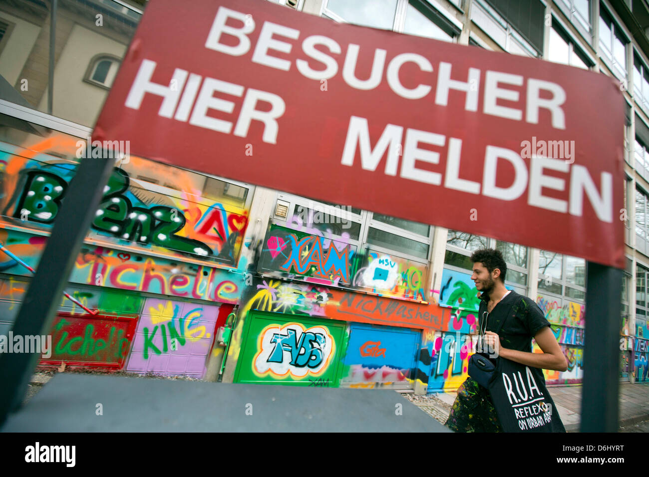 Brasilianischen Graffiti-Künstler Rimon Guimaraes geht vorbei an einer alten Zeichen für Besucher im ehemaligen Büro von der KfW, in Frankfurt Main, Deutschland, 18. April 2013 abgerissen werden soll. Graffiti-Künstler aus Deutschland und Brasilien bieten Workshops in der "Graffiti-Akademie" in Zusammenarbeit mit der Kunsthalle Schirn. Foto: FRANK RUMPENHORST Stockfoto