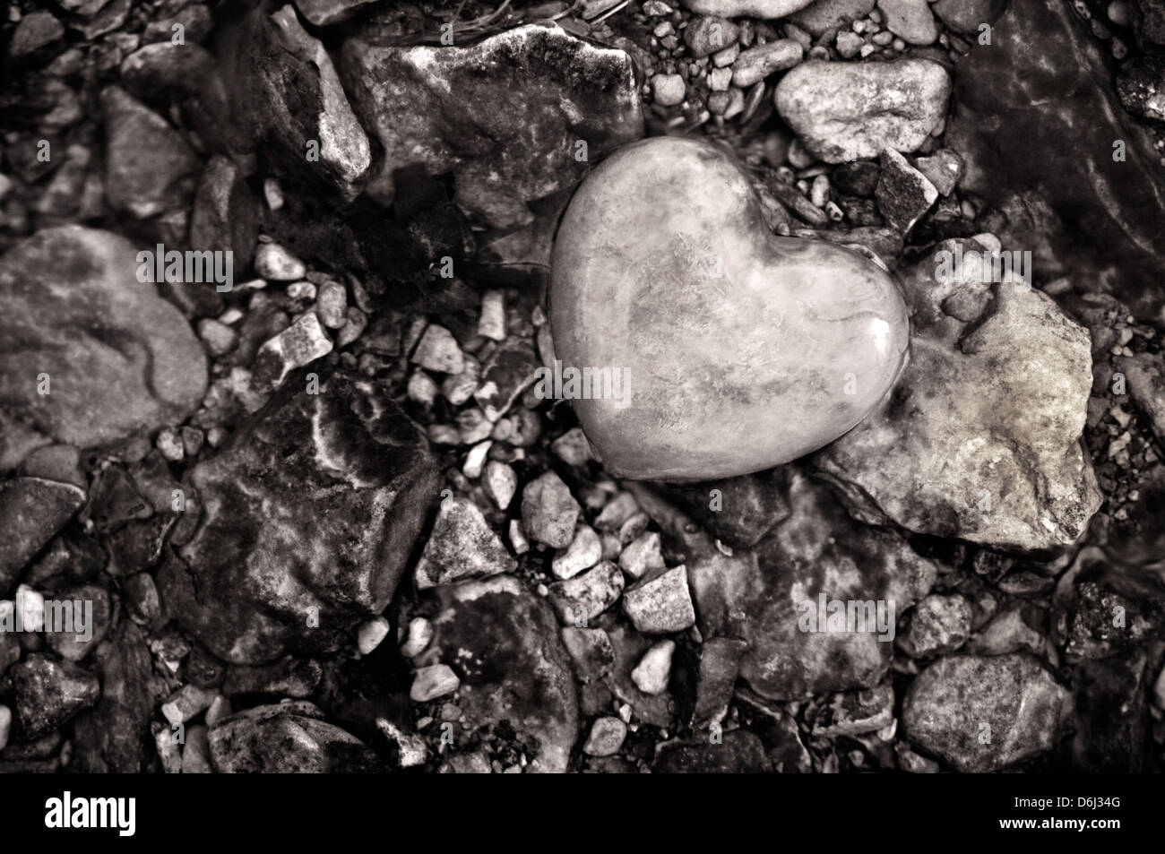 Schwarz / weiß steinerne Herz inmitten Kieselsteine in einem Stream Stockfoto