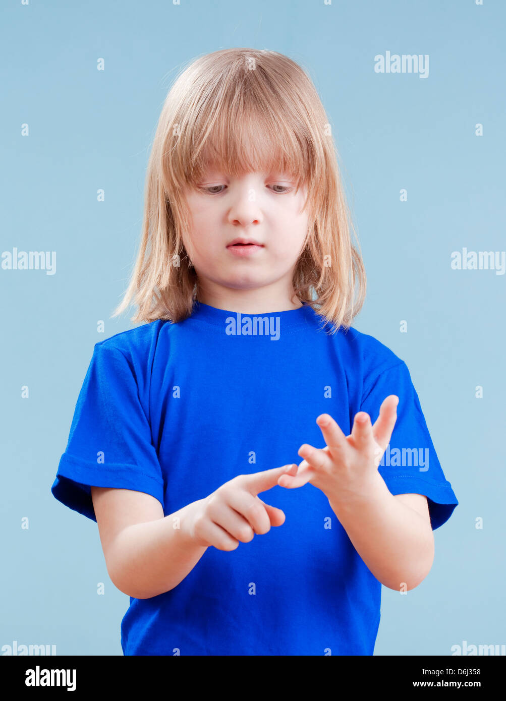 Junge mit langen blonden Haaren zählen auf Finger seiner Hand - isoliert auf blau Stockfoto