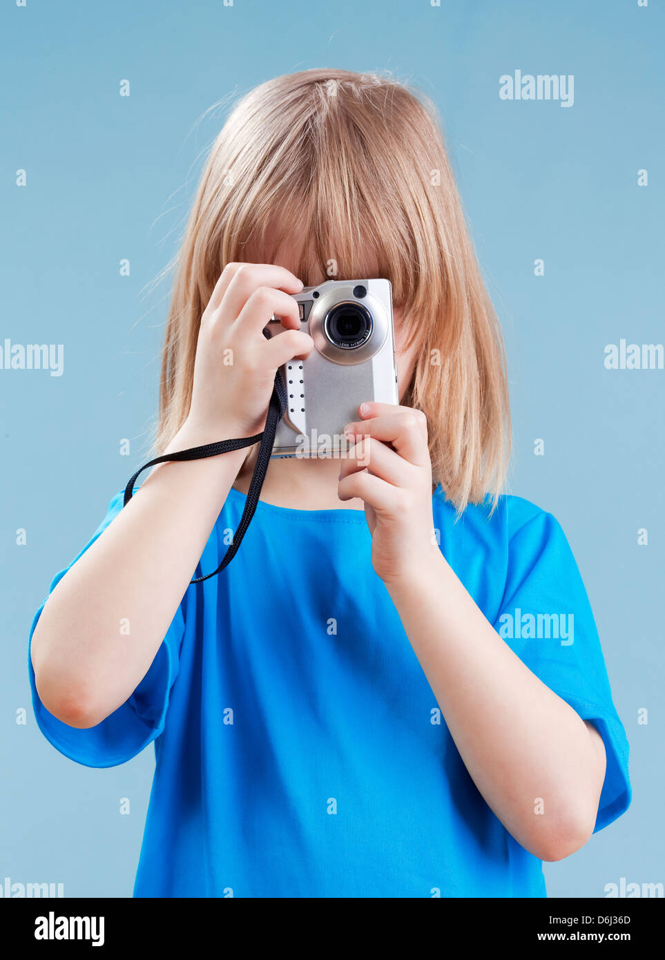 Junge mit langen blonden Haaren fotografieren mit Digitalkamera - isoliert auf blau Stockfoto