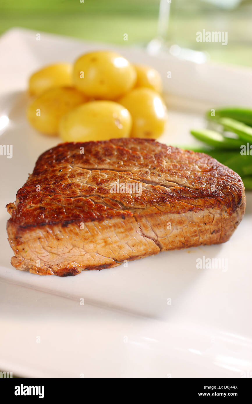 Filet Steak Rind Medaillon (Filet Mignon) mit Butter Babykartoffeln und Zuckerschoten auf einem quadratischen weißen Teller Zucker Stockfoto