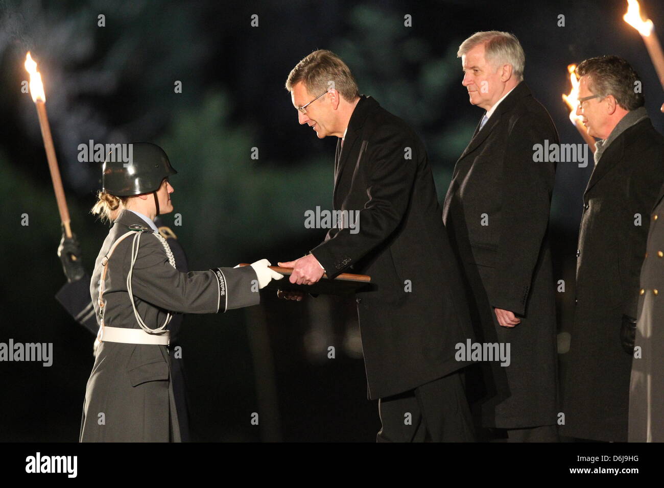 Ein Soldat übergibt ein Geschenk an früheren Bundespräsidenten Christian Wulff, neben dem provisorischen Präsidenten Horst Seehofer (2-R) und German Defence Minister Thomas de Maiziere (R) während der sogenannten "Grosser Zapfenstreich" (Grand Tattoo) initiiert, um Ehre Politiker Wulff vor dem Schloss Bellevue in Berlin, Deutschland, 8. März 2012. Wulff trat aus dem Amt am 17. Februar 2 Stockfoto