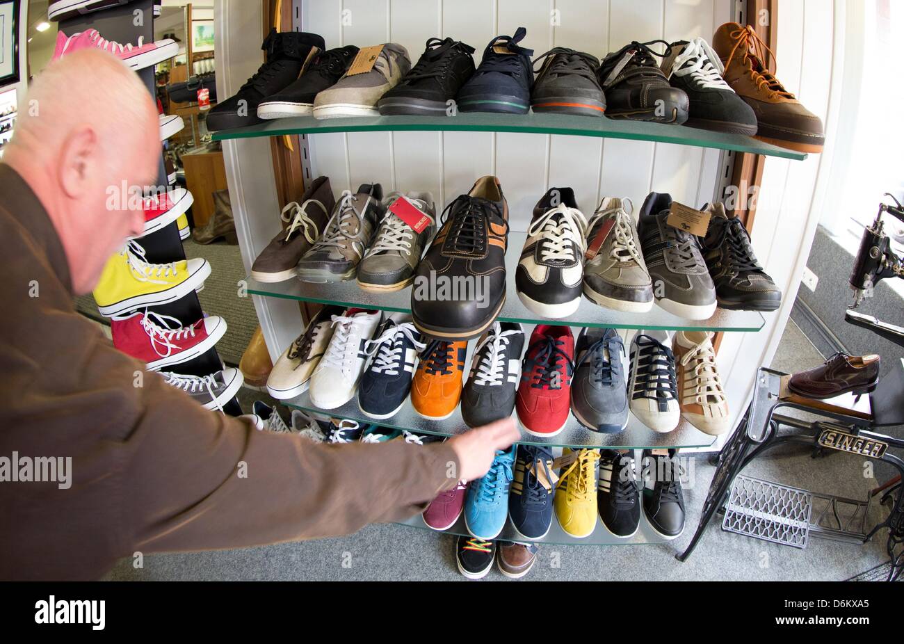 Schuster Georg Wessels stellt übergroße Schuhe auf einem Regal in seinem  Geschäft in Vreden, Deutschland, 15.