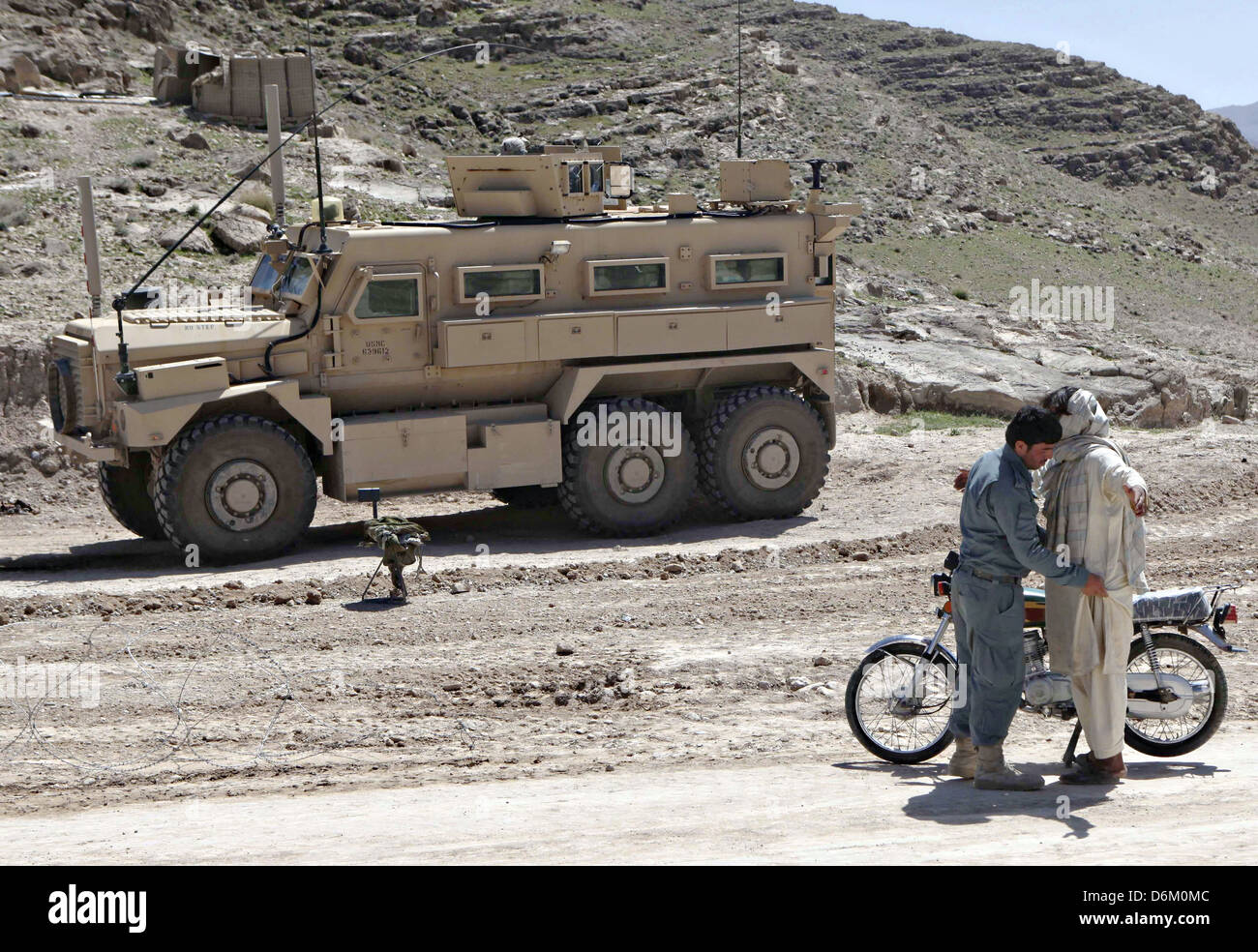 Ein afghanischer Polizist Uniform sucht einen Motorradfahrer an einem Kontrollpunkt entlang Route Route 611 30. März 2013 in der Nähe von Outpost Torioba, Provinz Helmand, Afghanistan. Stockfoto