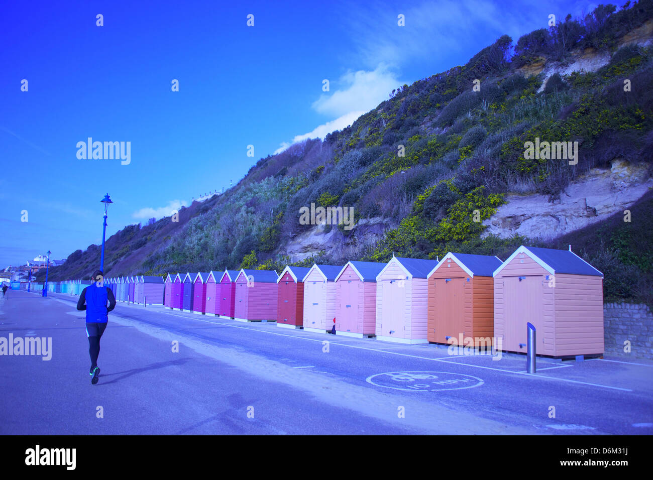 Britische Küste und Strand-Hütte in Bournemouth - Promenaden ein Jogger Farbe und Kunst, die in die Ferne führt. Stockfoto