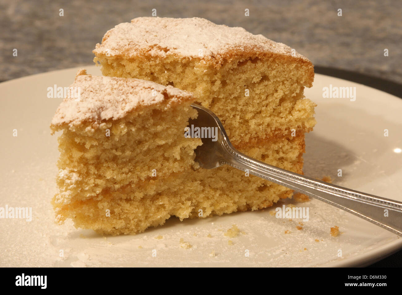 Eine Scheibe Zitrone Biskuit ist mit einer Kuchengabel geschnitten wird. Stockfoto