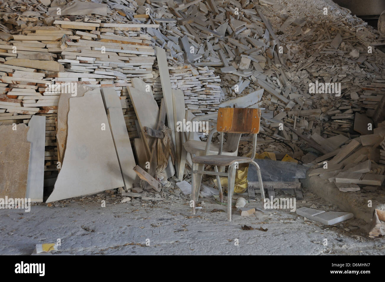 Staubige Stuhl und Haufen von gebrochenen Marmor in verlassenen Fabrik innen. Stockfoto