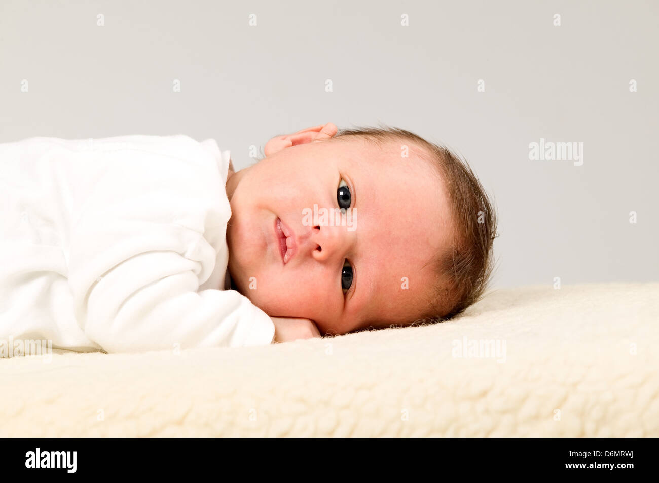 Baby Boy mit weißen Hemden liegt auf pelzigen Decke Stockfoto