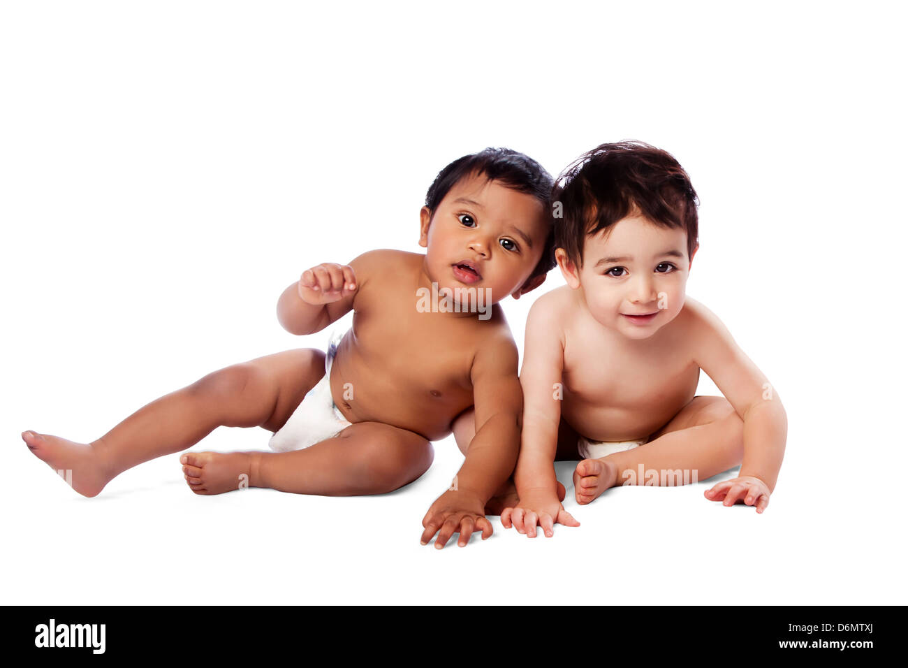 Zwei niedliche liebenswert multiethnischen Babys zusammensitzen, Kindheit Konzept auf weiß. Stockfoto