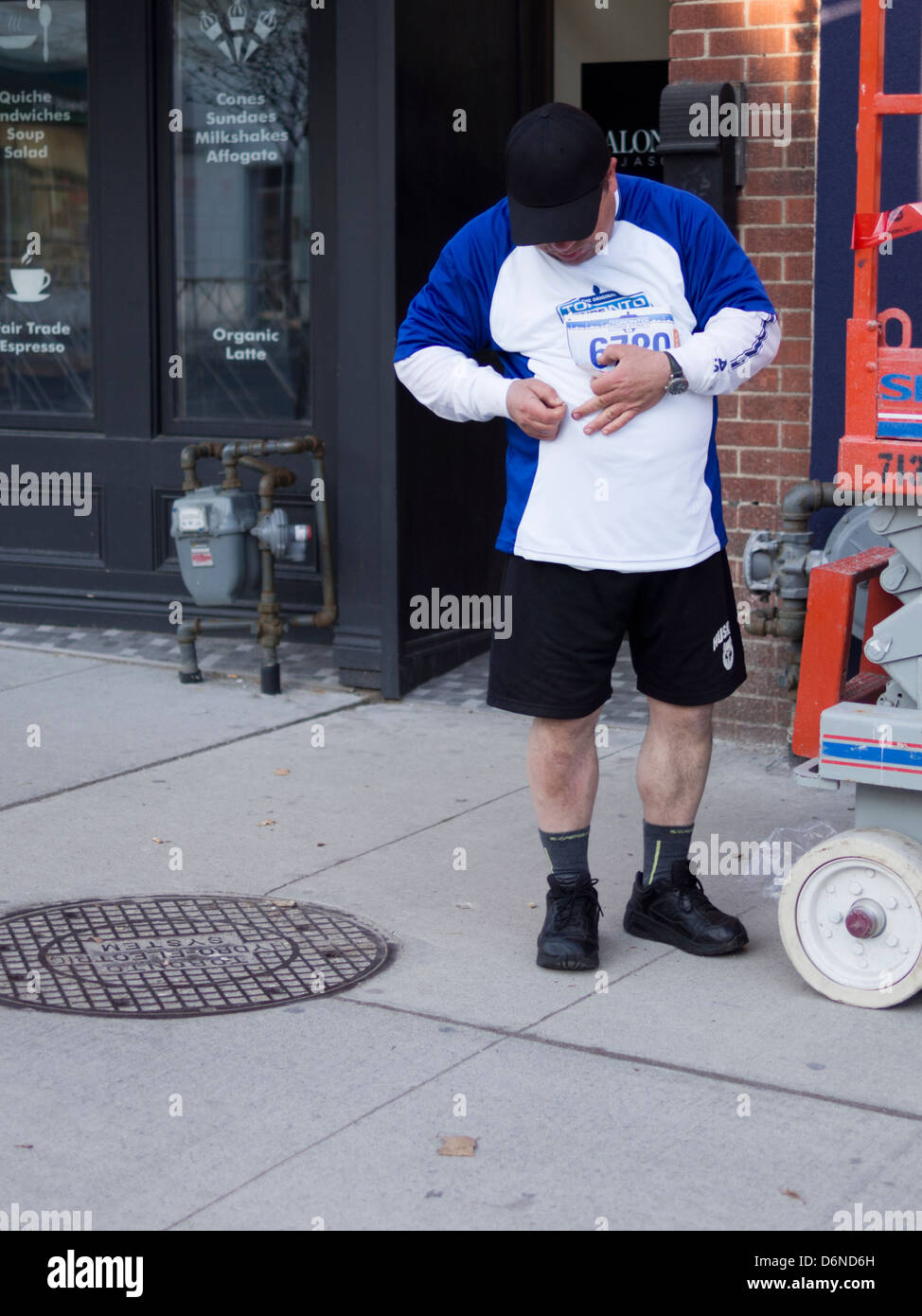 Ein Läufer pins seine Startnummer zu seinem blauen und weißen Hemd vor 2013 Toronto Yonge Street 10 K laufen Stockfoto