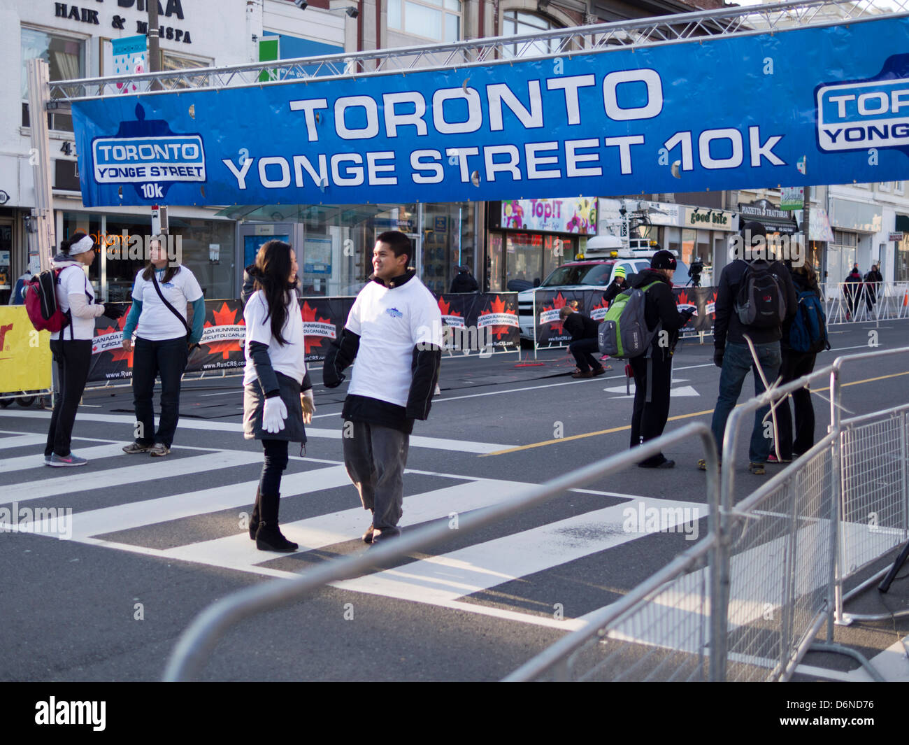 Freiwillige stehen unter dem blauen-weißen Zeichen bezeichnen die Start-Lüge von der 2013 Toronto Yonge Street 10K laufen Stockfoto