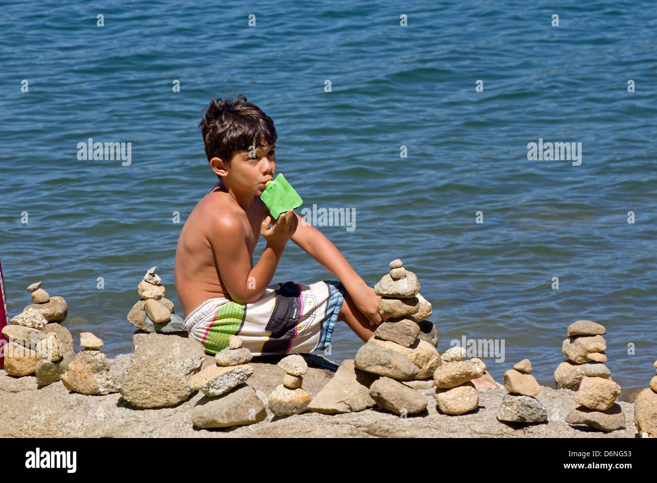 Kleiner Junge Am Strand Mit Haufen Von Gestapelten Steinen Um Ihn Herum Sitzen Er Ist Braun Und 