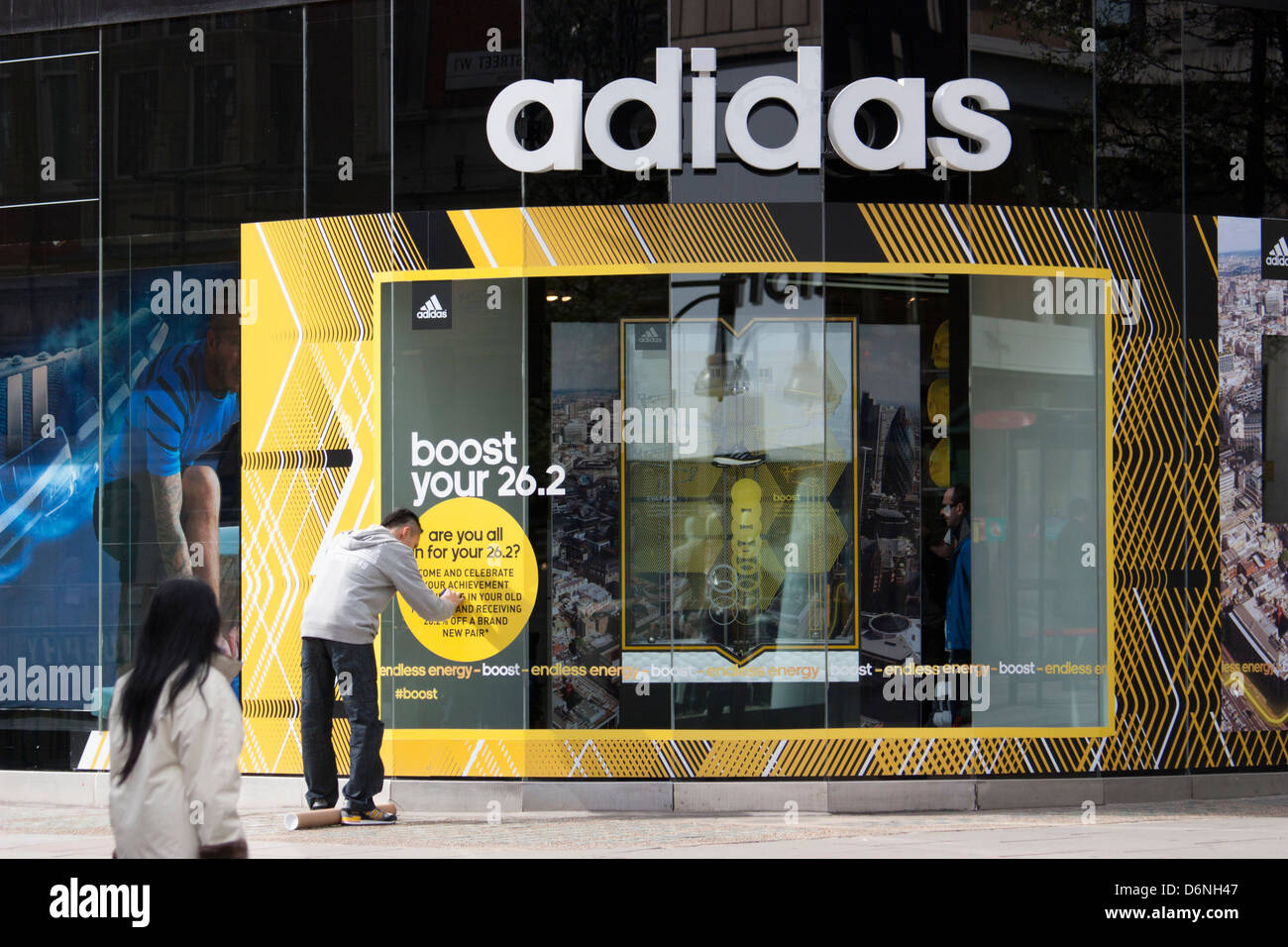 Adidas store Oxford Street London, Shop Arbeiter Pasten Logo außerhalb Shops Stockfoto