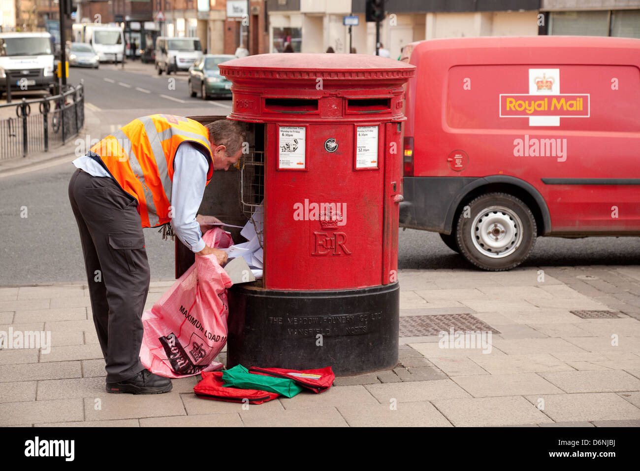 Ein Royal Mail Postbote UK Entleerung e-Mails aus einer Mailbox, mit seinem roten Royal Mail van, York, Yorkshire UK Stockfoto
