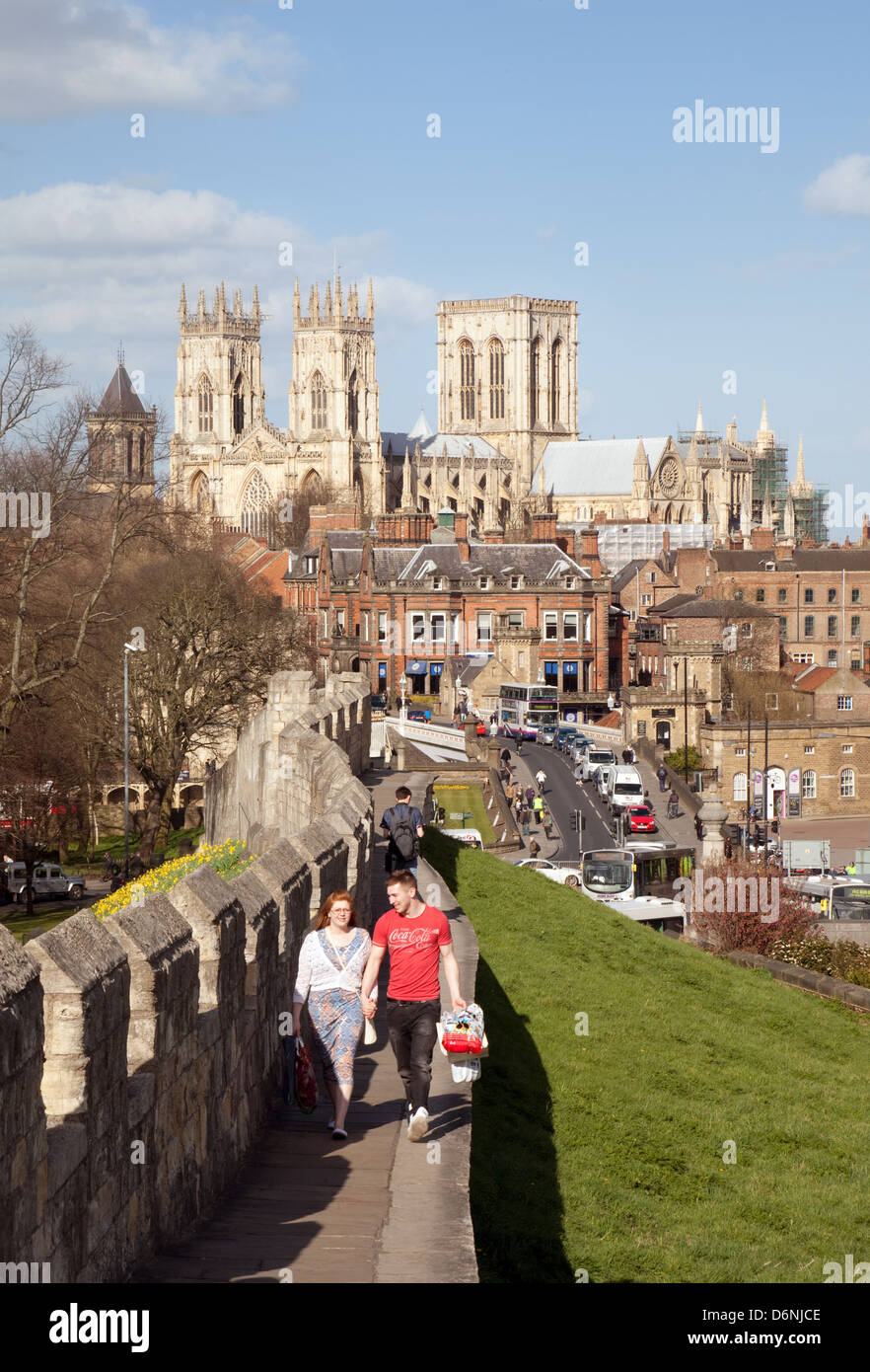 Stadtmauern von York; Menschen, die die alten Stadtmauern mit der York Minster Kathedrale im Hintergrund, York, Yorkshire UK, spazieren Stockfoto