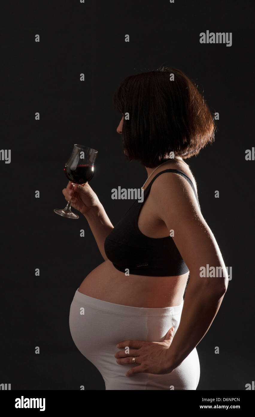 Freiburg, Deutschland, eine schwangere Frau mit einem Glas Rotwein Stockfoto