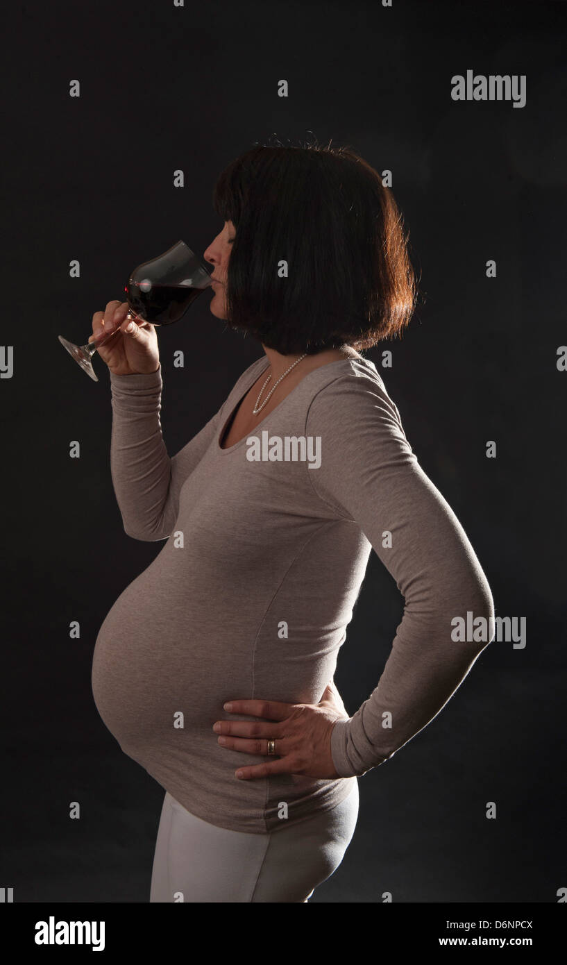 Freiburg, Deutschland, eine schwangere Frau mit einem Glas Rotwein Stockfoto