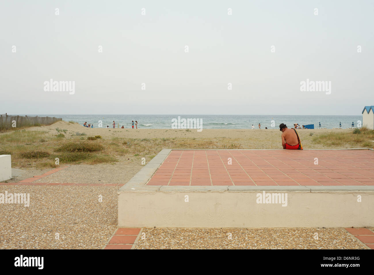 Le Barcares, Frankreich, Mann mit Hut sitzt am Strand promenade in den Badeort Le Barcares Stockfoto