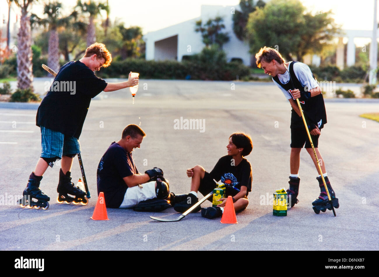 Jugendliche spielen Streethockey zusammen, dösen, Hänseleien, spielen Stockfoto