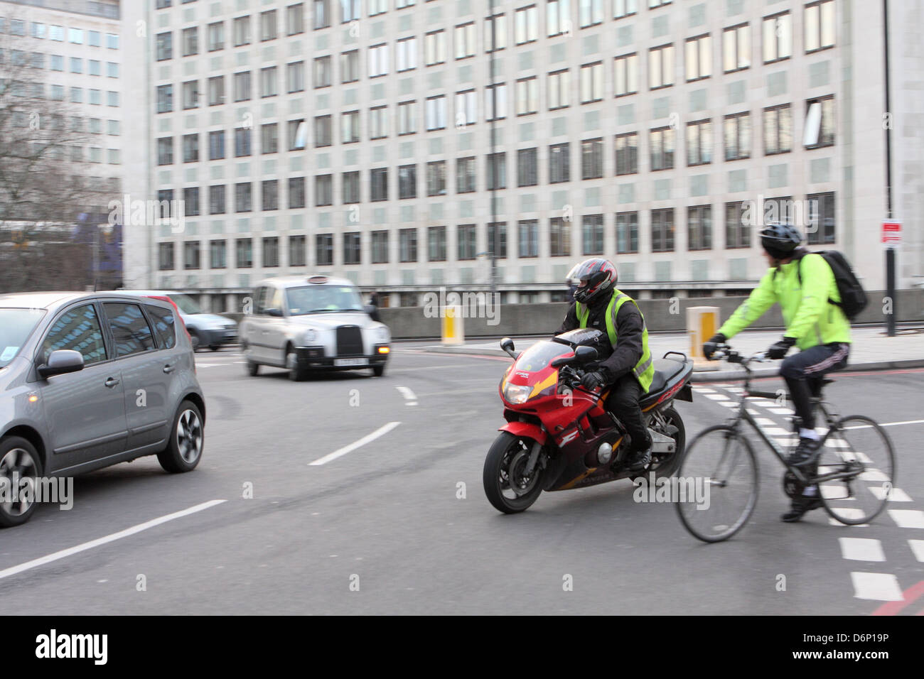 Ein Motorradfahrer und ein Radfahrer in einem Kreisverkehr in London, England. Stockfoto